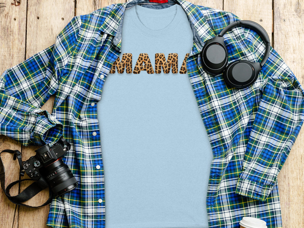 Light blue t-shirt with "MAMA" in leopard print letters, open plaid shirt, headphones, and camera.