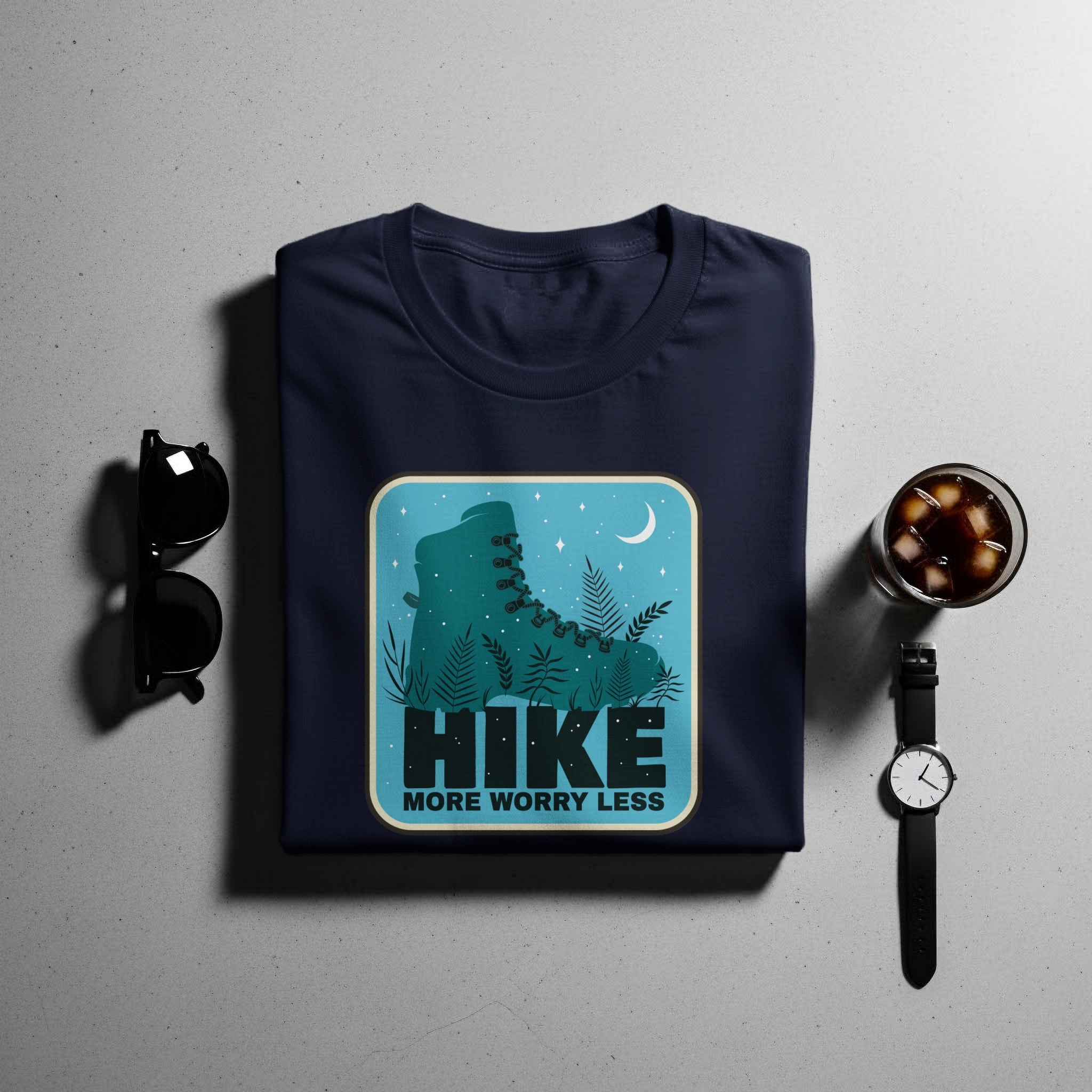 Dark navy t-shirt with a graphic of a teal hiking boot and text that says "HIKE MORE WORRY LESS".