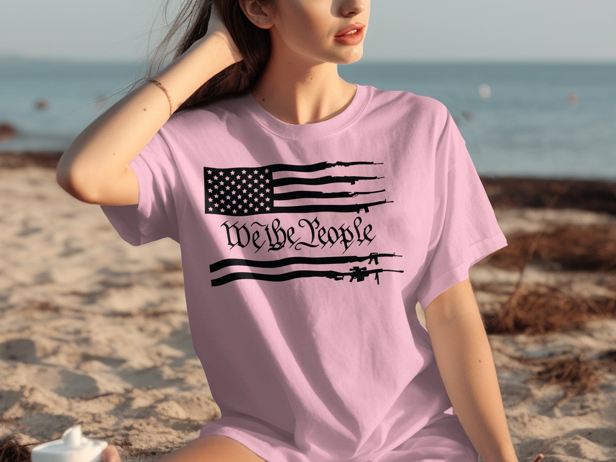 Pink t-shirt with a black flag design featuring guns and the text "We the People."