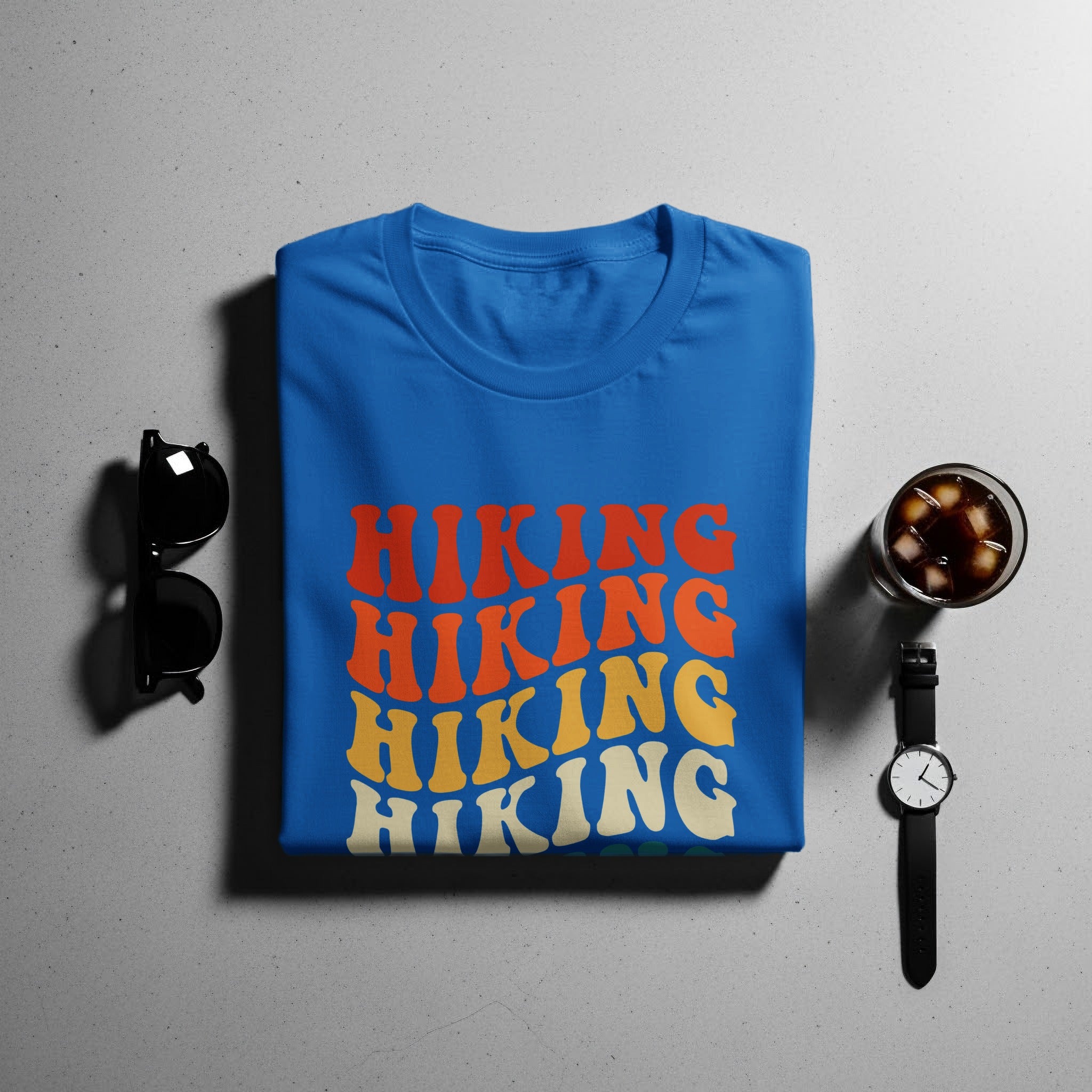 Blue t-shirt with "HIKING" repeated in retro, wavy font in orange, yellow, and cream.