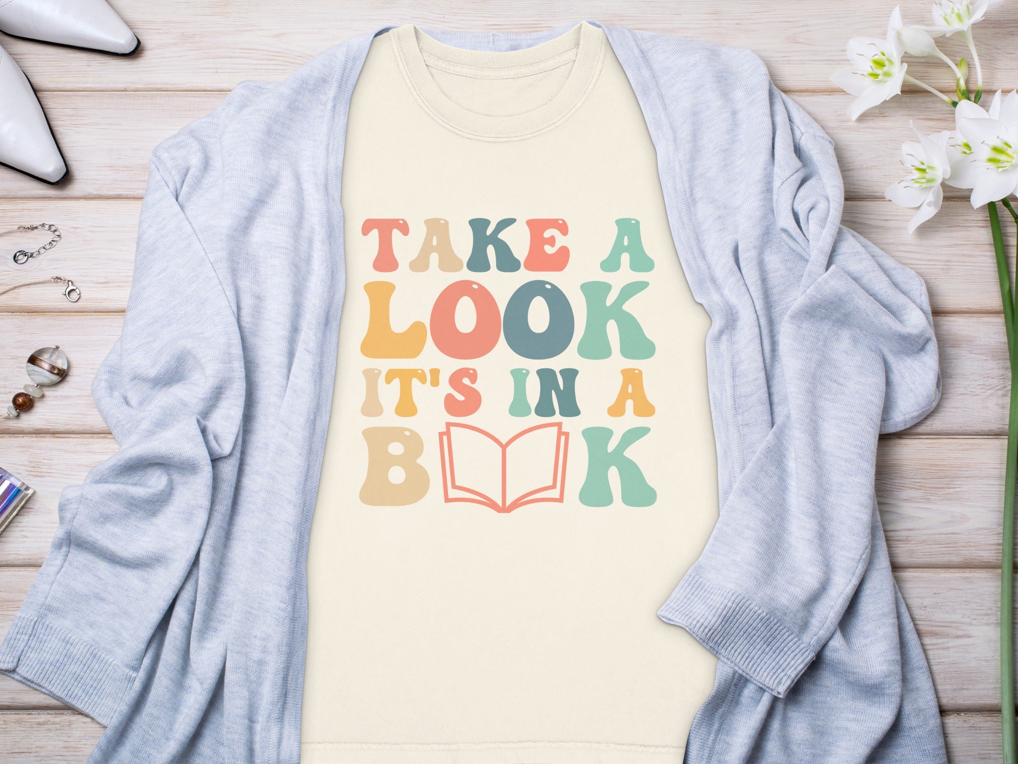T-shirt with "TAKE A LOOK IT'S IN A BOOK" text and an open book graphic.