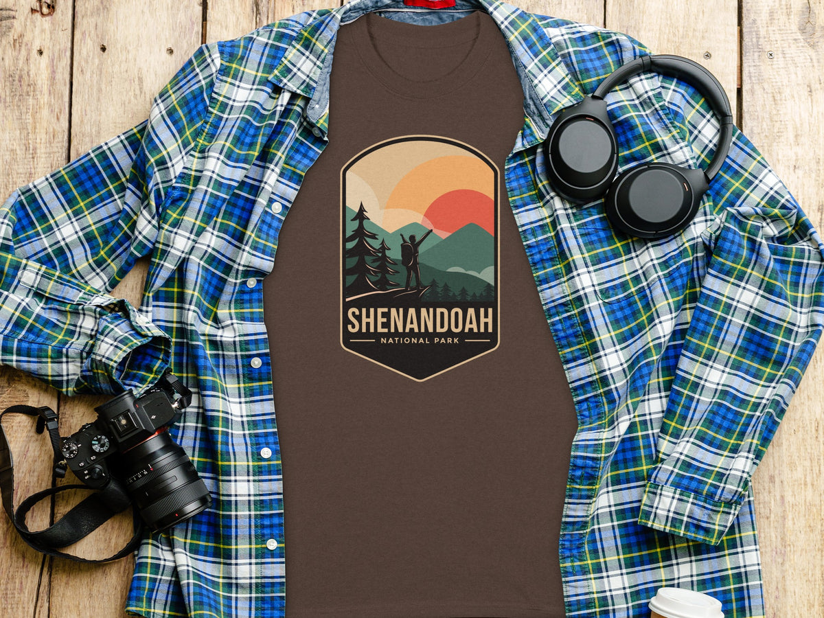 Brown t-shirt with Shenandoah National Park graphic, plaid shirt, headphones, and camera.