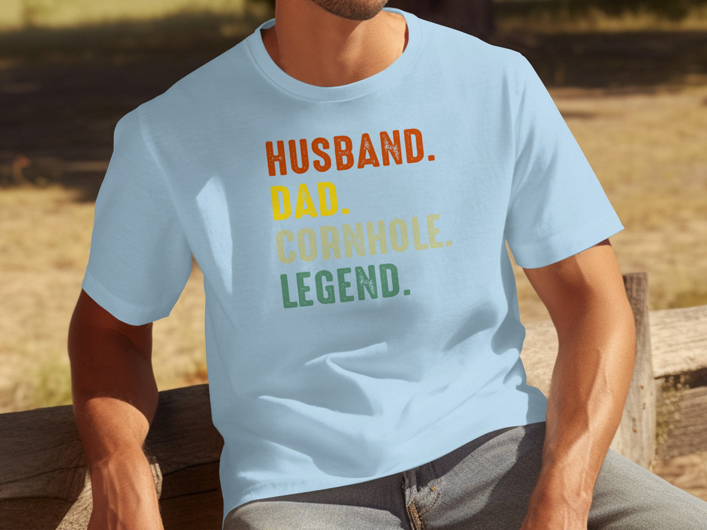 Light blue t-shirt reads "Husband. Dad. Cornhole. Legend." in distressed vintage text.