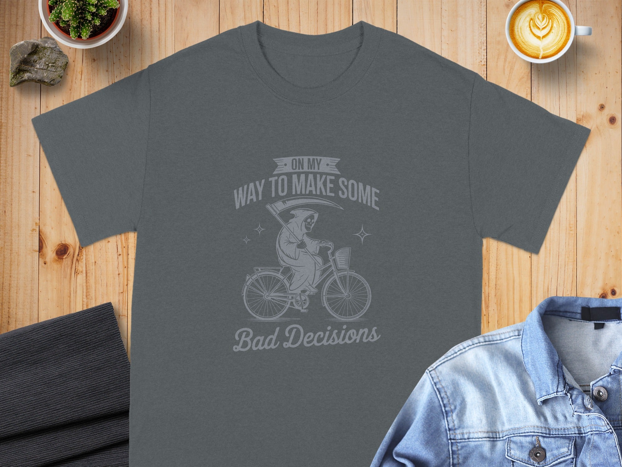 Dark grey t-shirt with grim reaper riding a bicycle graphic and text.
