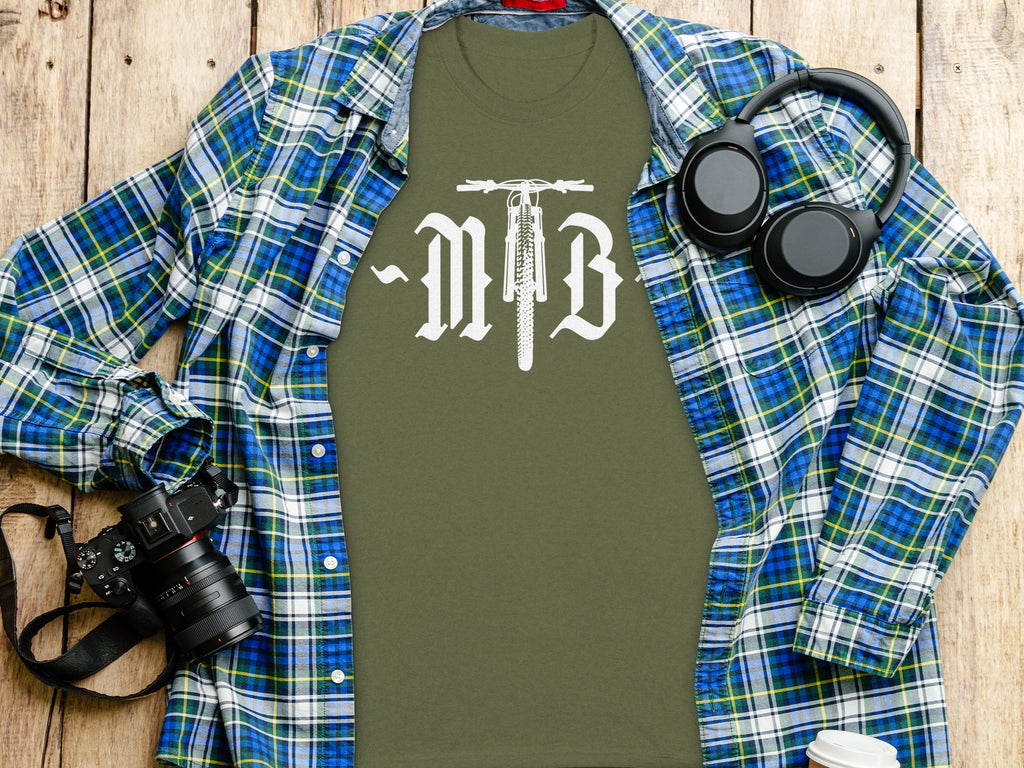Olive green t-shirt with 'MTB' and bicycle graphic, worn under plaid shirt.