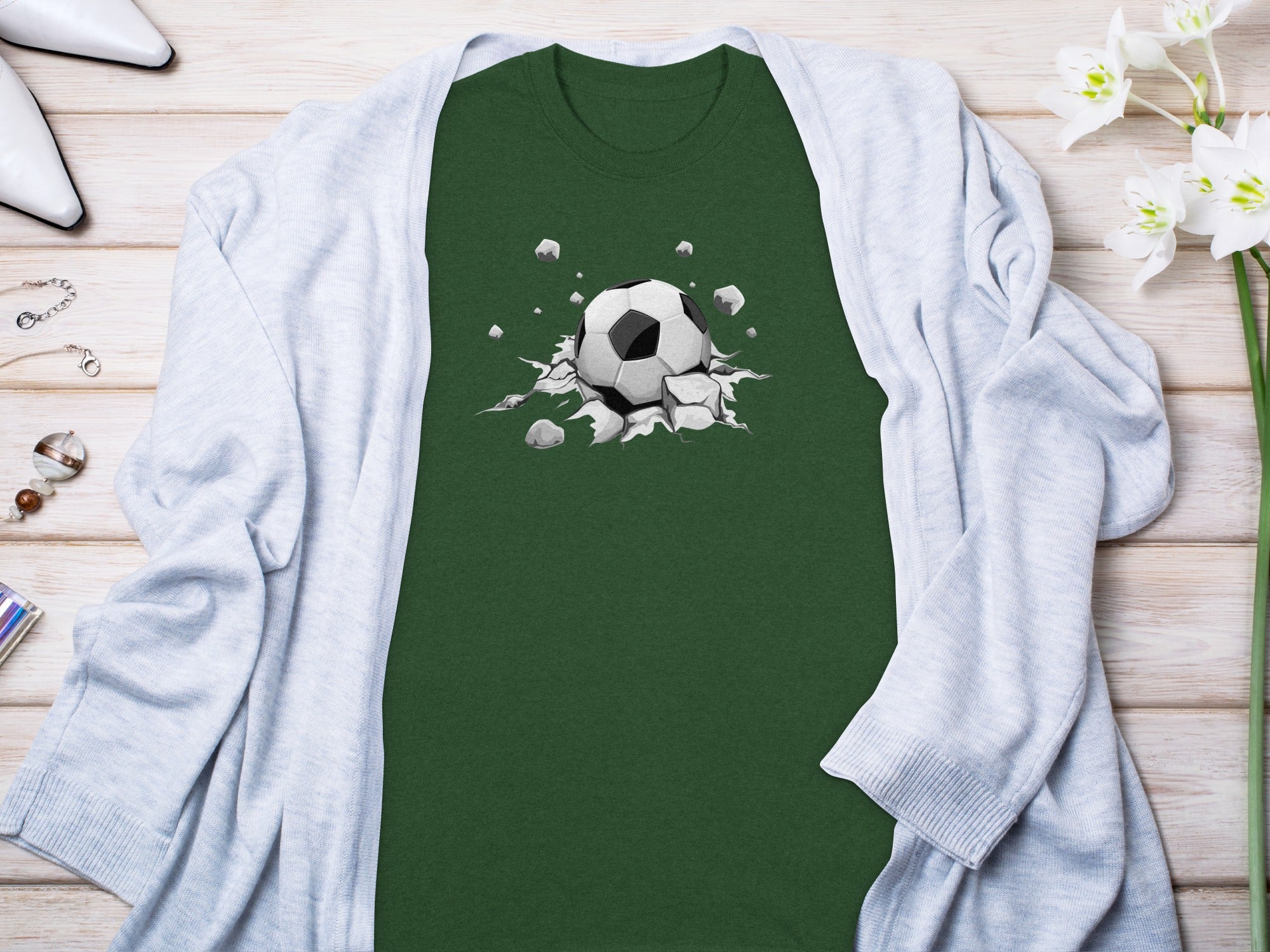 Green t-shirt with a soccer ball breaking through a cracked surface graphic.