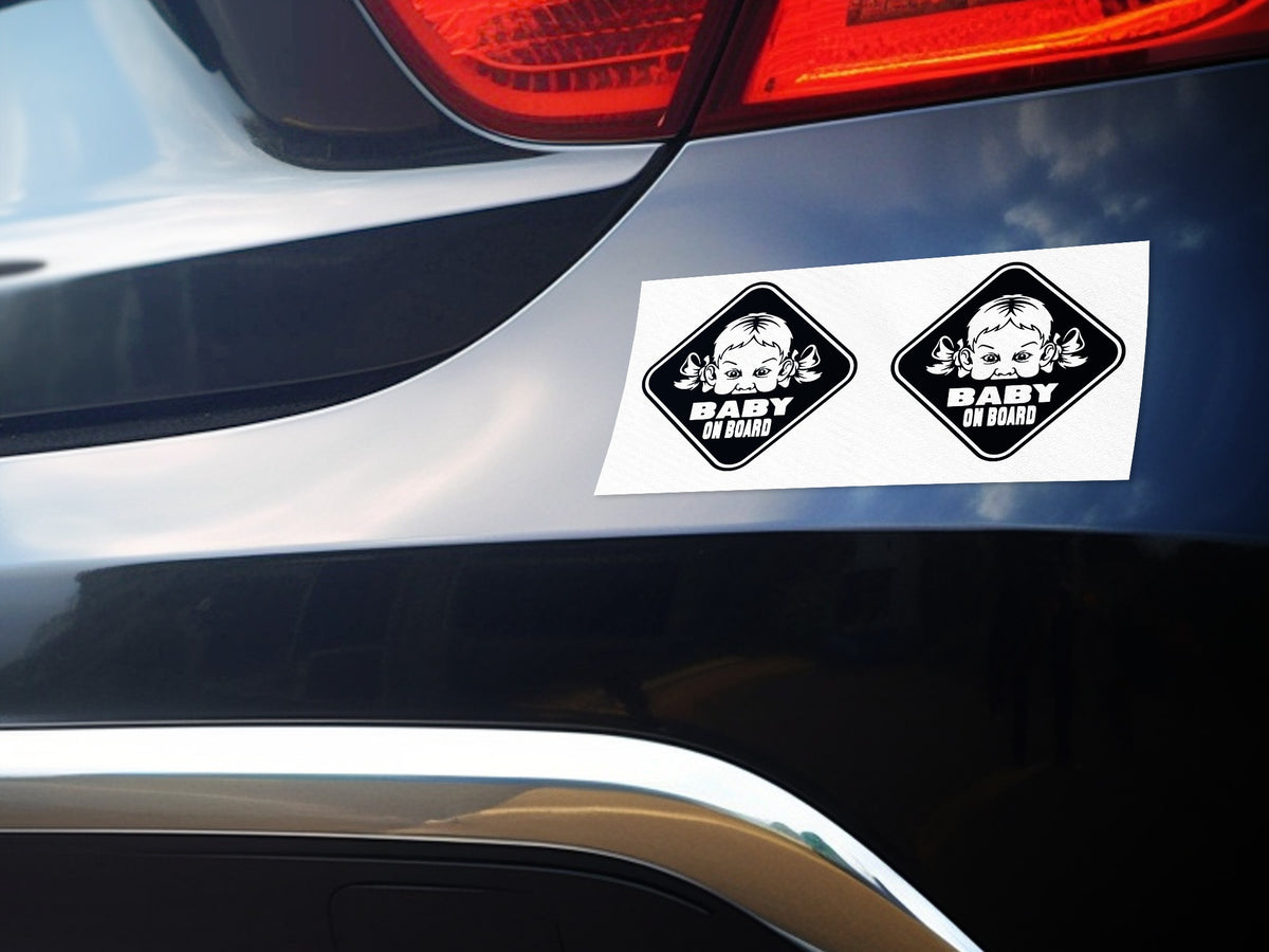 Two diamond-shaped "Baby on Board" stickers with a baby's face, placed on a car's trunk.