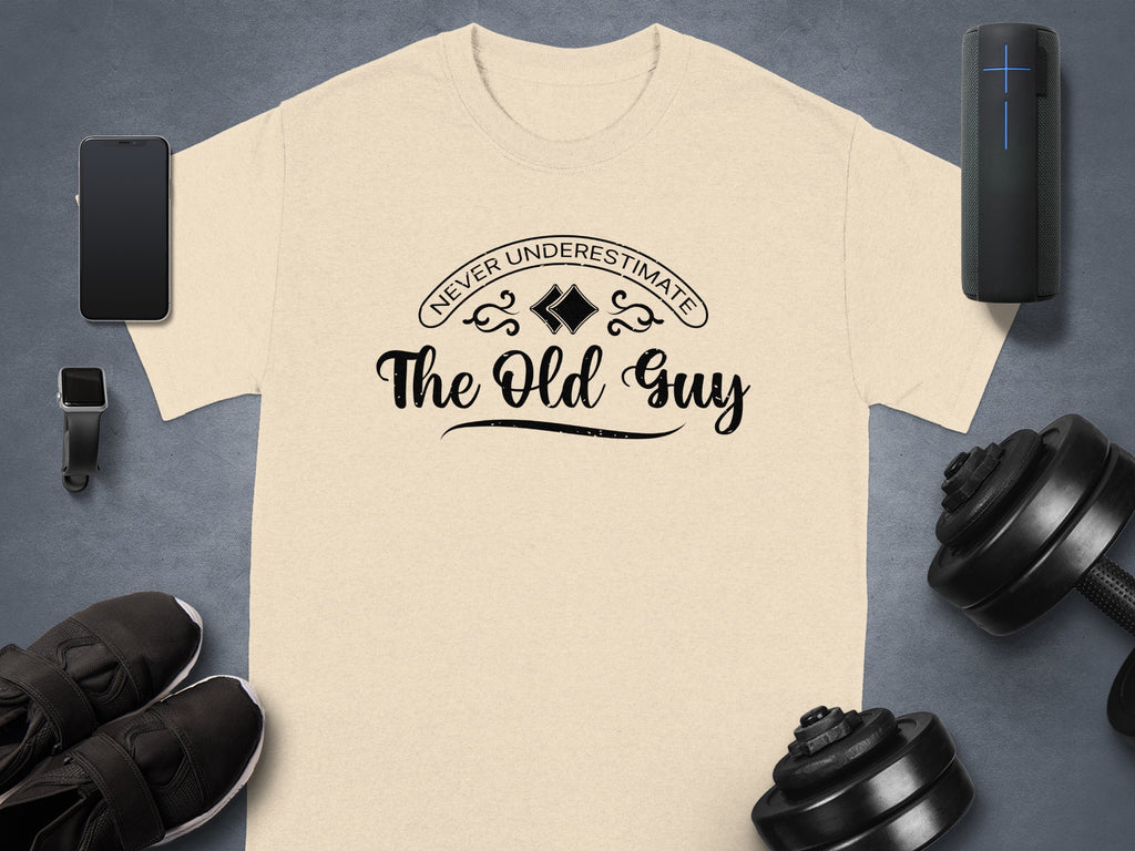 Beige t-shirt with black text "NEVER UNDERESTIMATE The Old Guy".