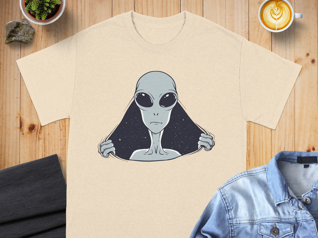 Cream t-shirt with a graphic of a gray alien emerging from a starfield.