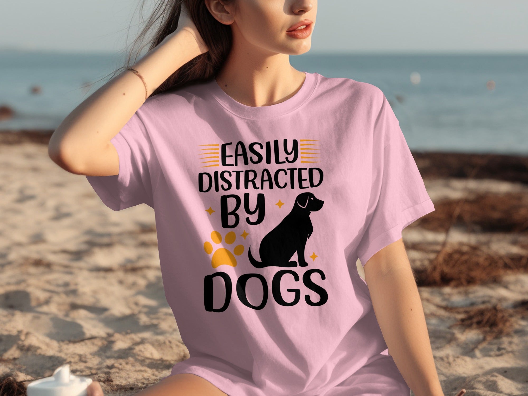 Pink t-shirt with black text and graphics reading "Easily Distracted By Dogs."