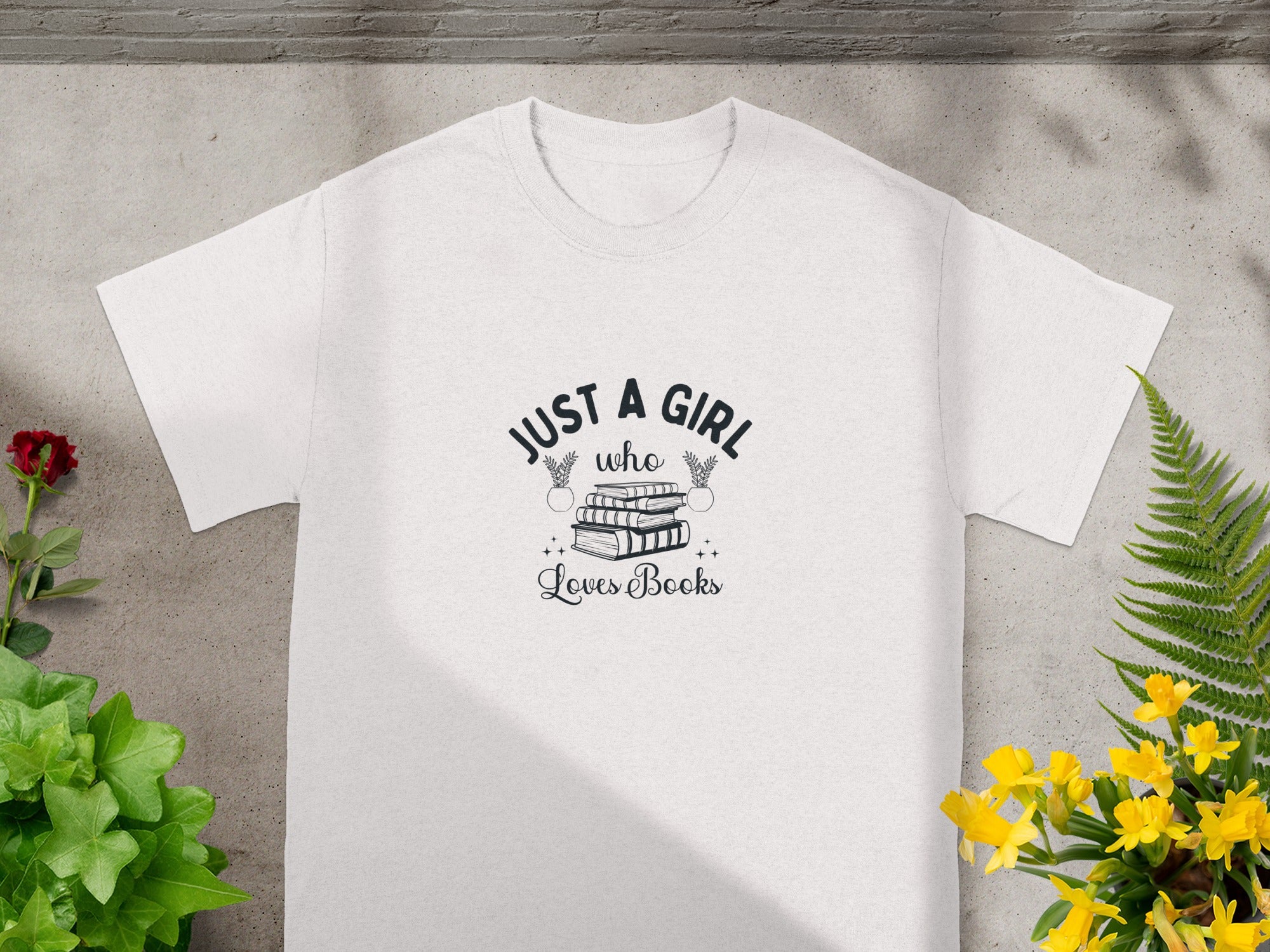 White t-shirt with "Just a girl who loves books" text and book illustration.