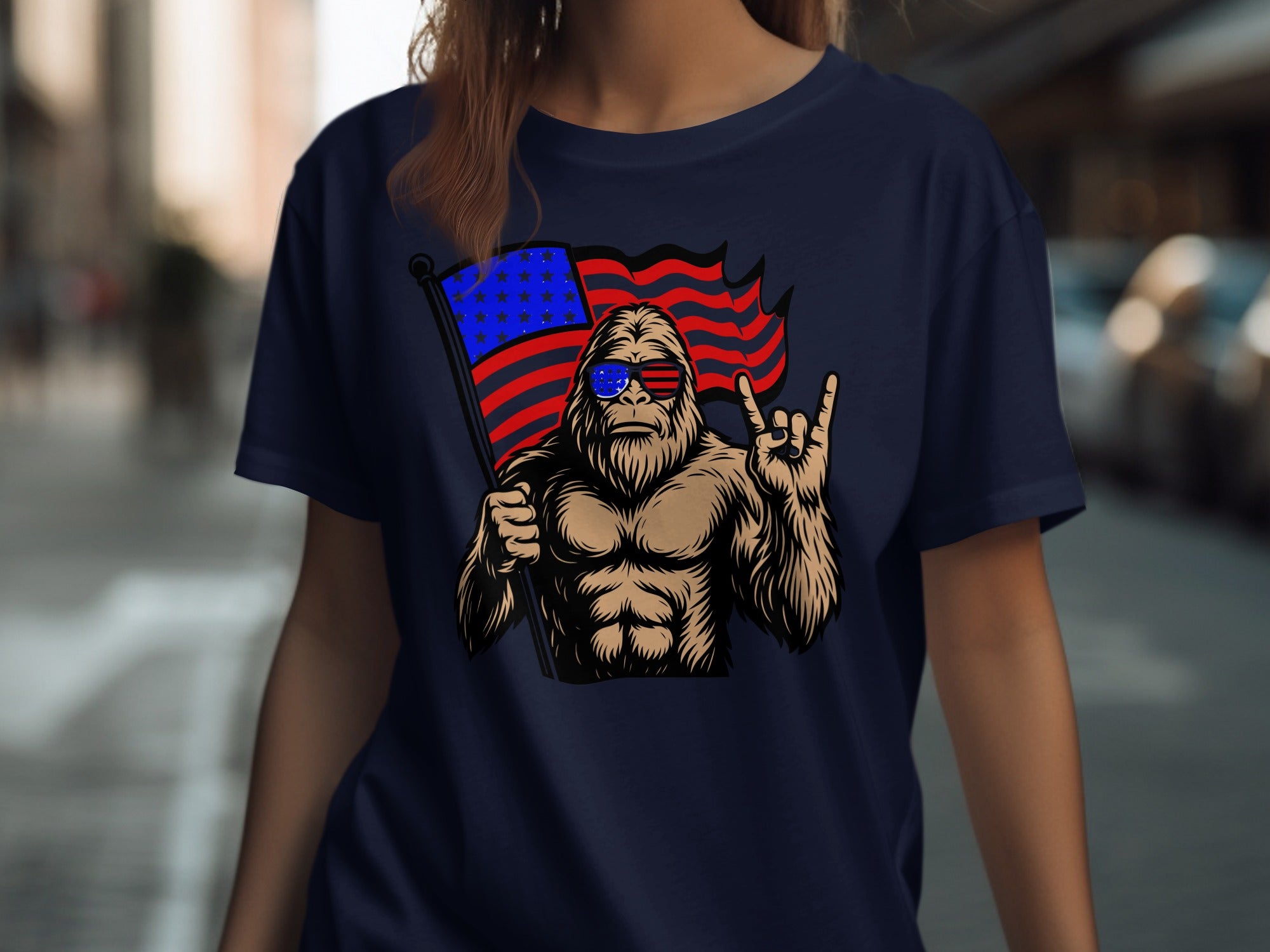 Bigfoot wearing sunglasses and holding an American flag, giving a rock-on hand gesture.