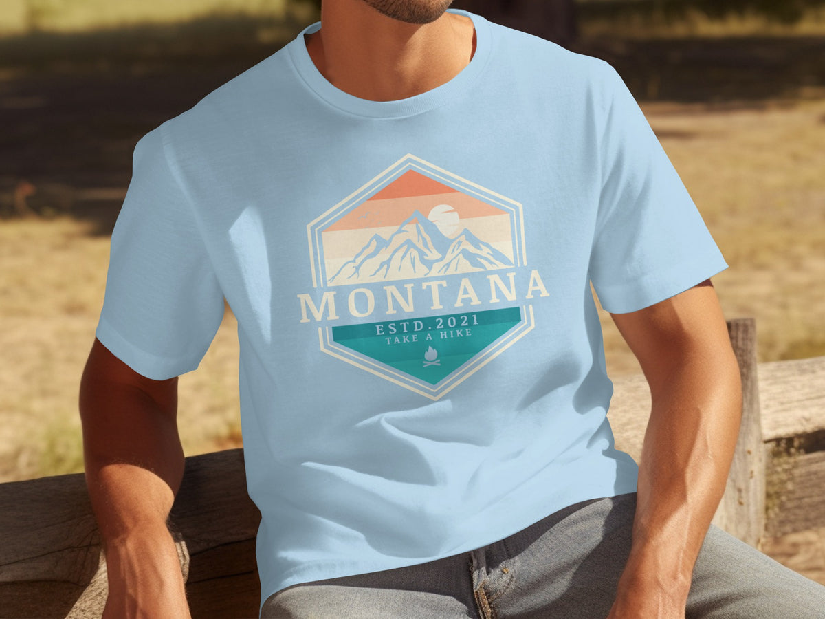 Light blue t-shirt with Montana mountain graphic, ESTD. 2021, and campfire icon.