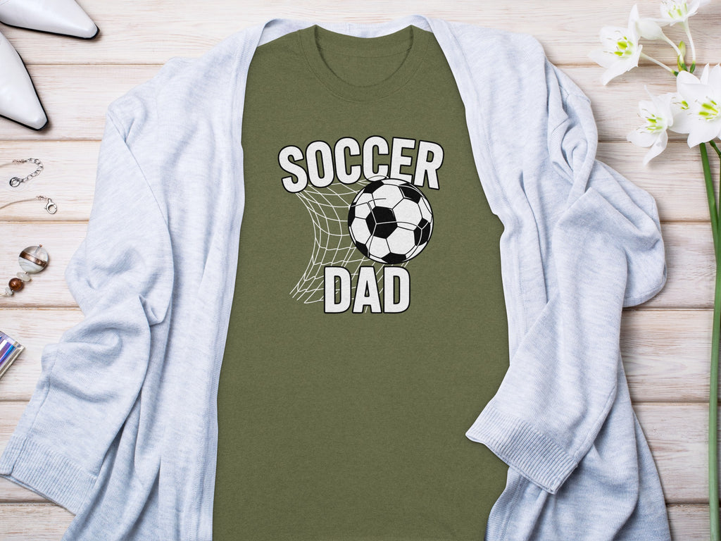Olive green t-shirt with "SOCCER DAD" graphic and soccer ball in net.