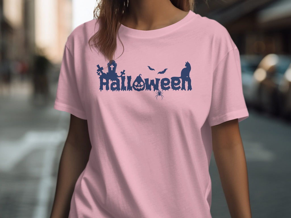 Pink t-shirt with navy blue Halloween graphic featuring graves, pumpkin, bats, spider, and cat.