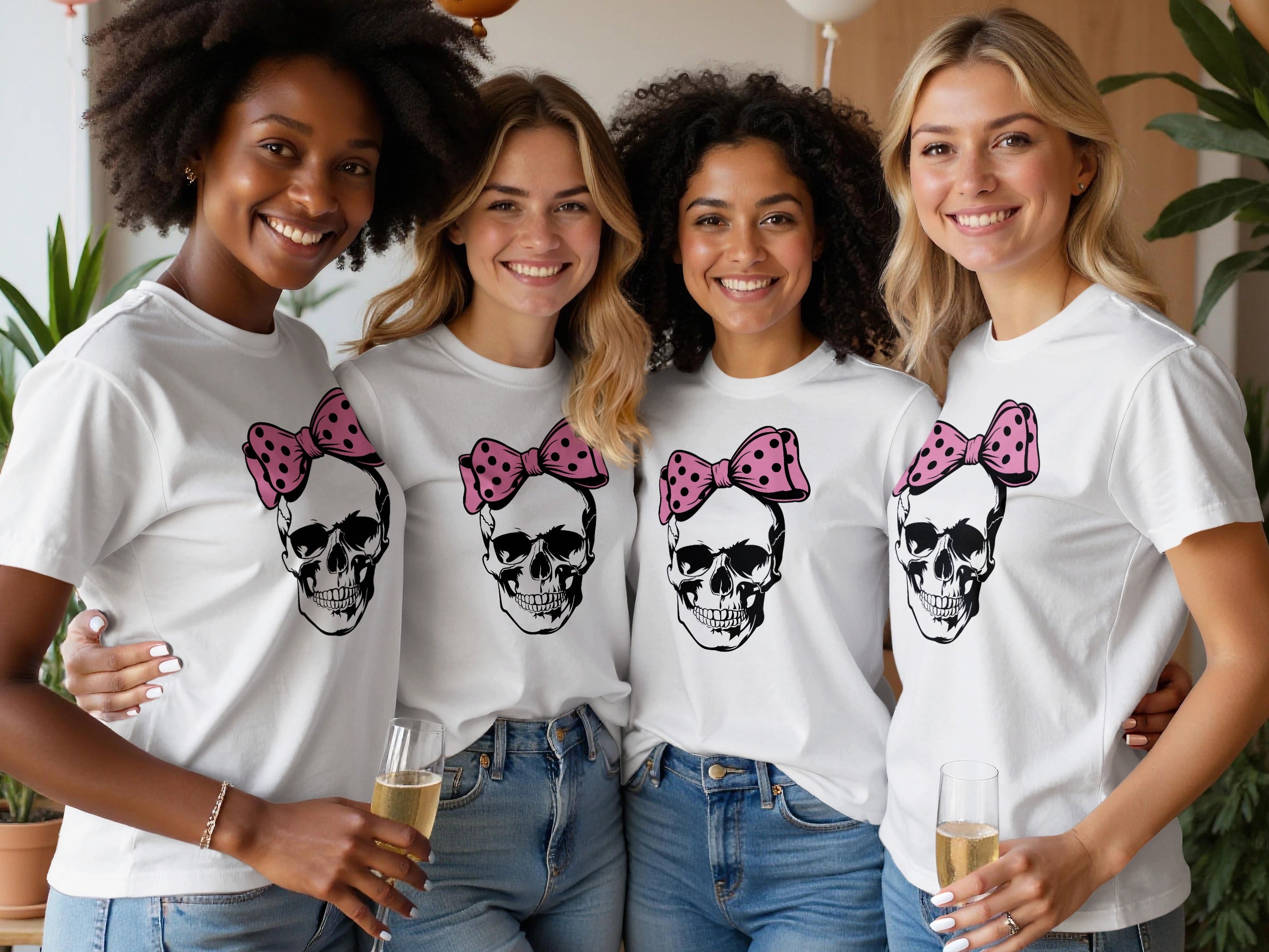 Four smiling women in white t-shirts with skull and pink bow graphic.