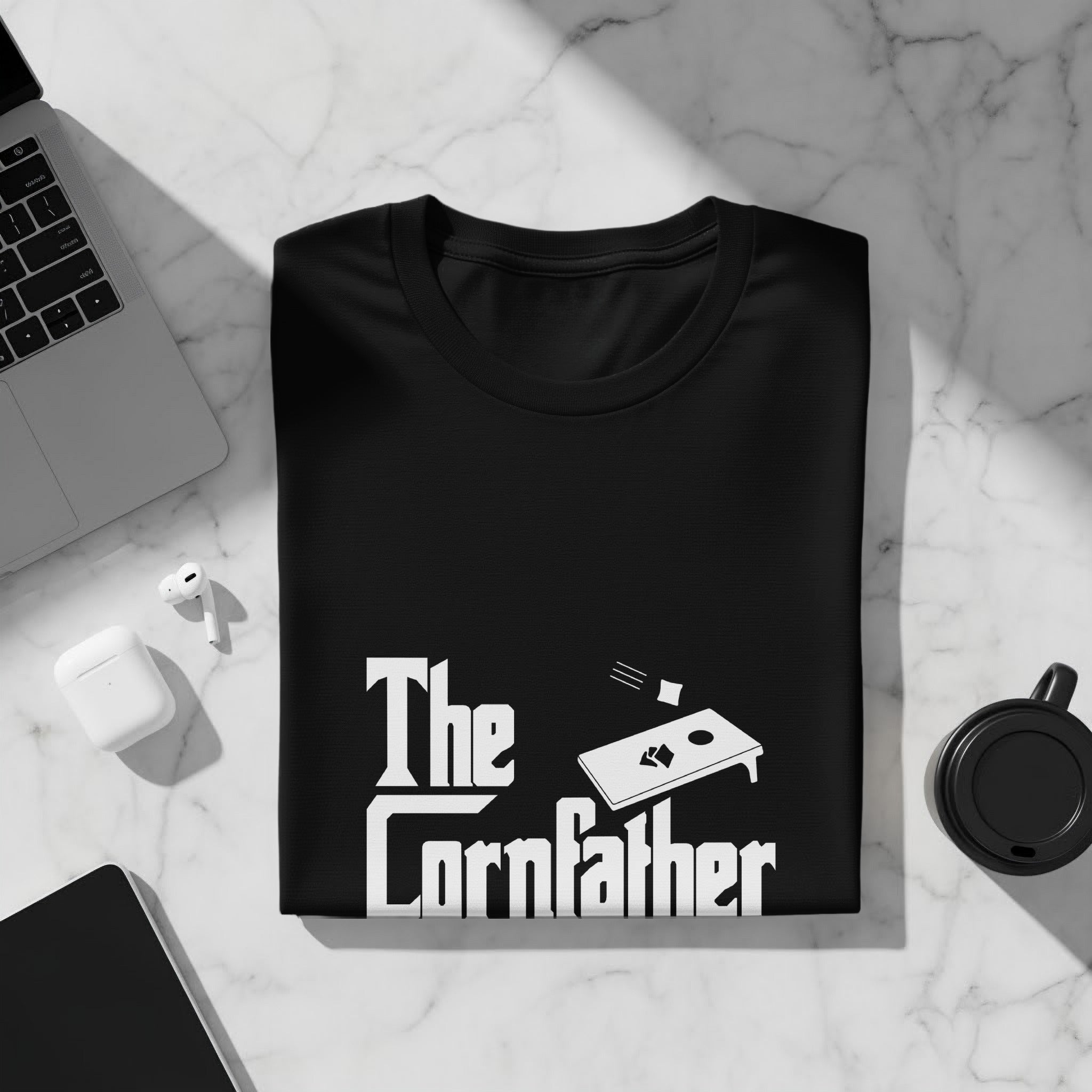 Black t-shirt with "The Cornfather" text and cornhole board imagery.
