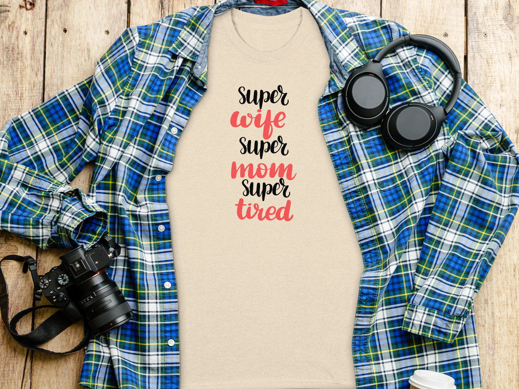 Light tan t-shirt with "Super wife super mom super tired" text, plaid shirt, headphones, and camera.