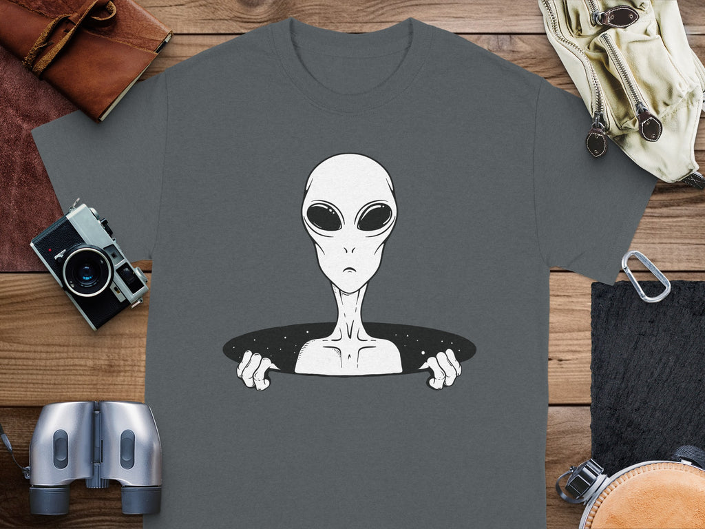 T-shirt with a grey alien peeking through a starry hole.