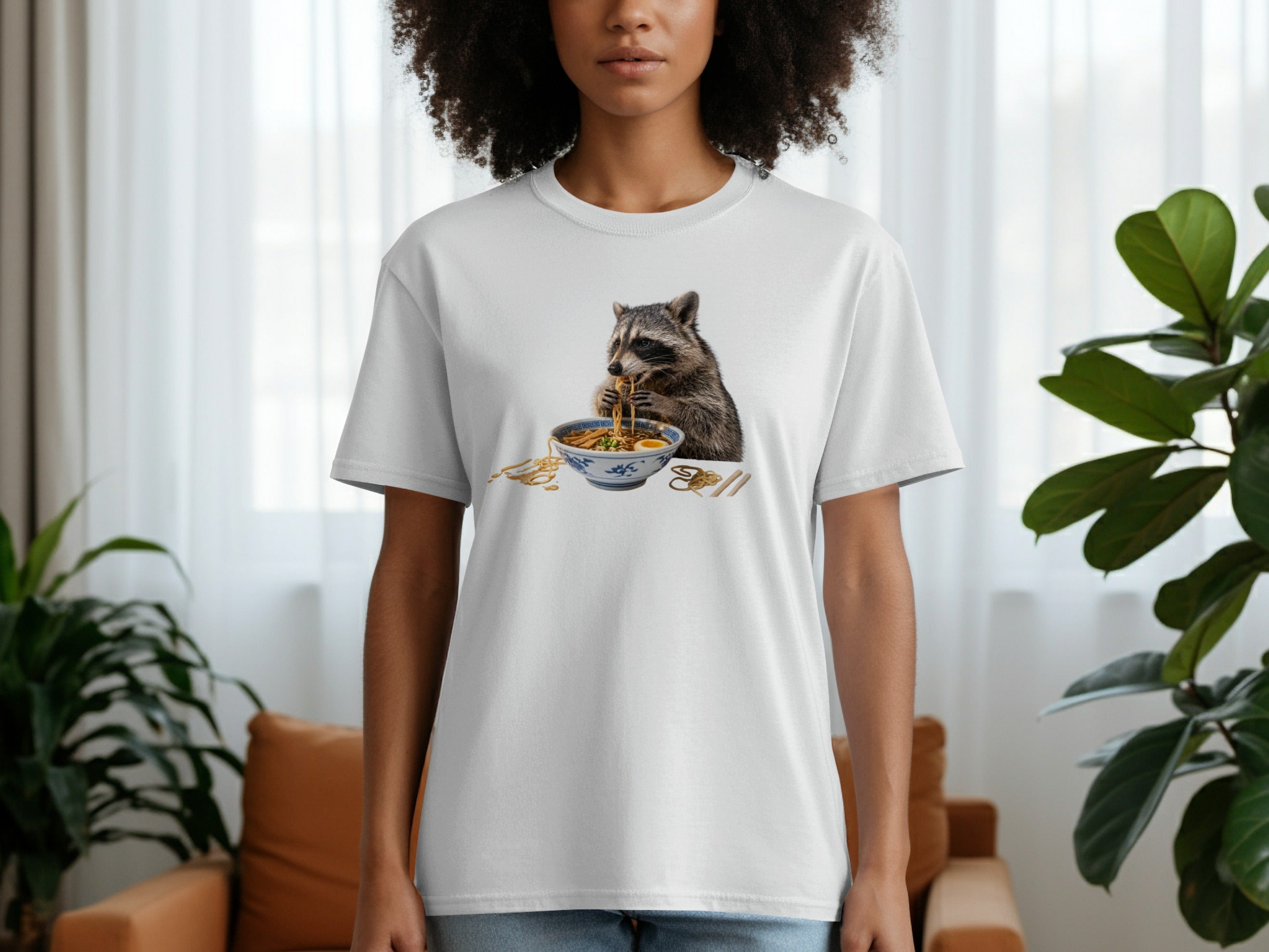 White t-shirt with a raccoon eating ramen noodles from a bowl.