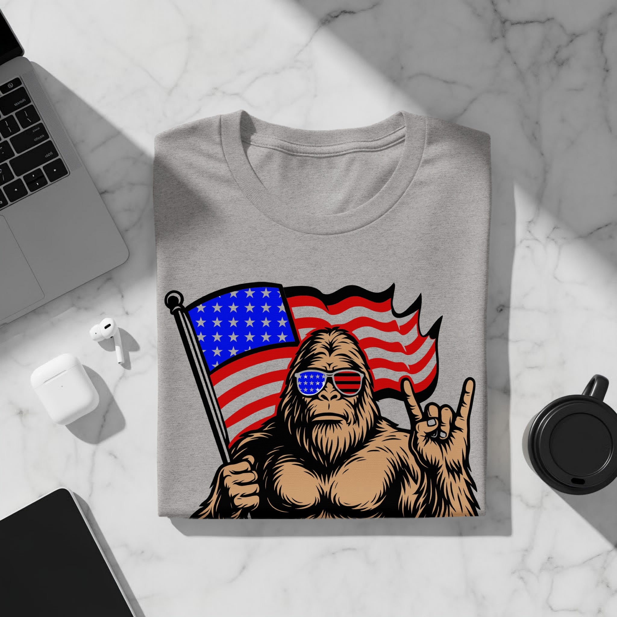 Bigfoot wearing patriotic sunglasses holds American flag and makes rock on gesture.