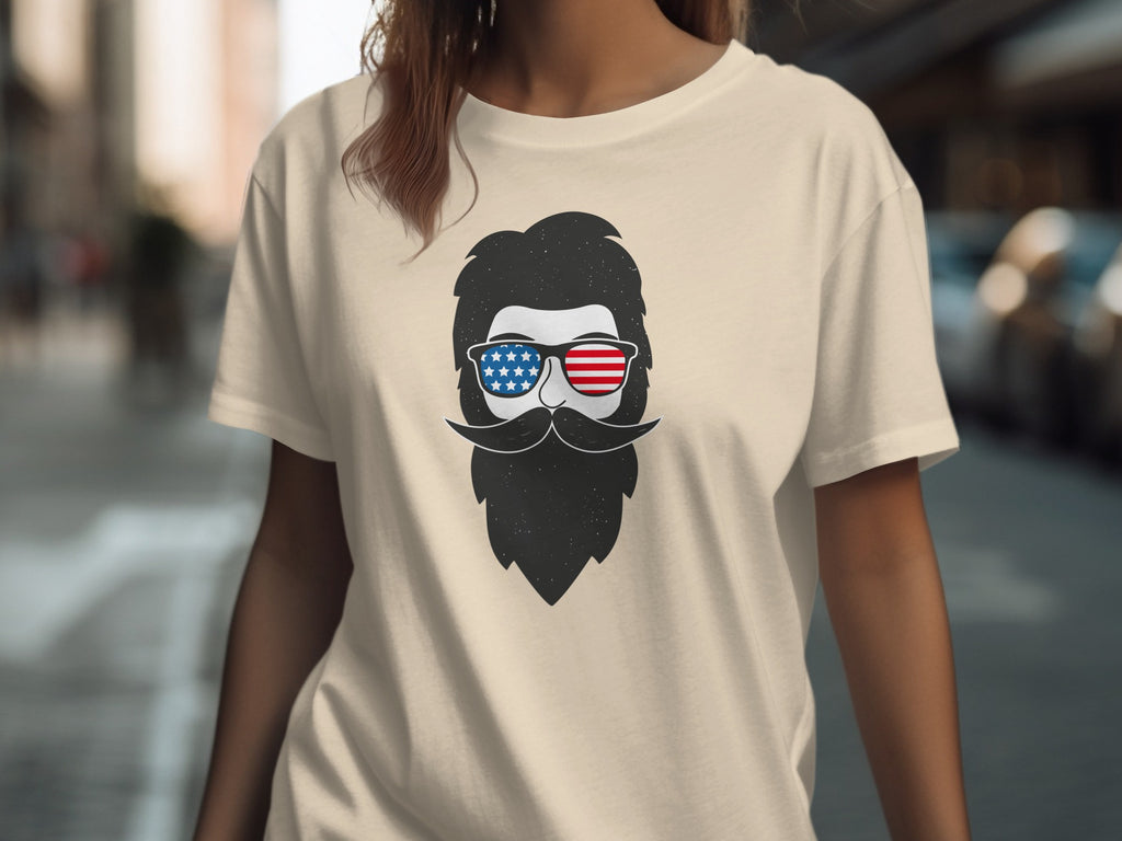 Cream t-shirt with graphic of bearded man wearing American flag sunglasses.
