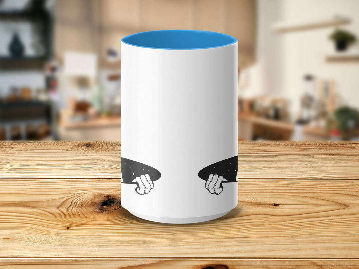 White mug with blue interior and graphic of hands holding a starry night.