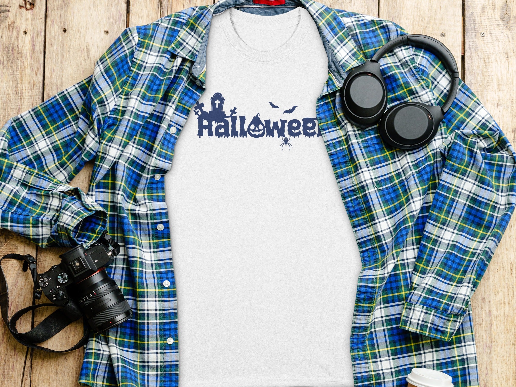 White t-shirt with blue Halloween graphic, plaid shirt, headphones, and camera.