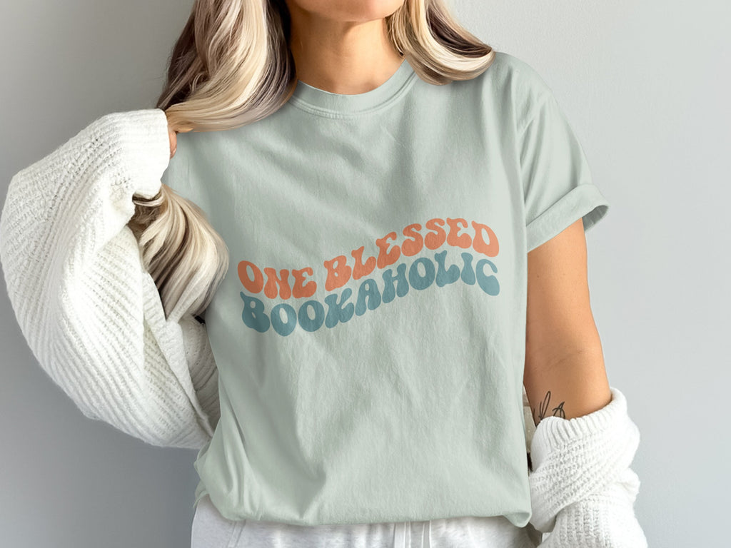 Light blue t-shirt with retro text "ONE BLESSED BOOKAHOLIC".