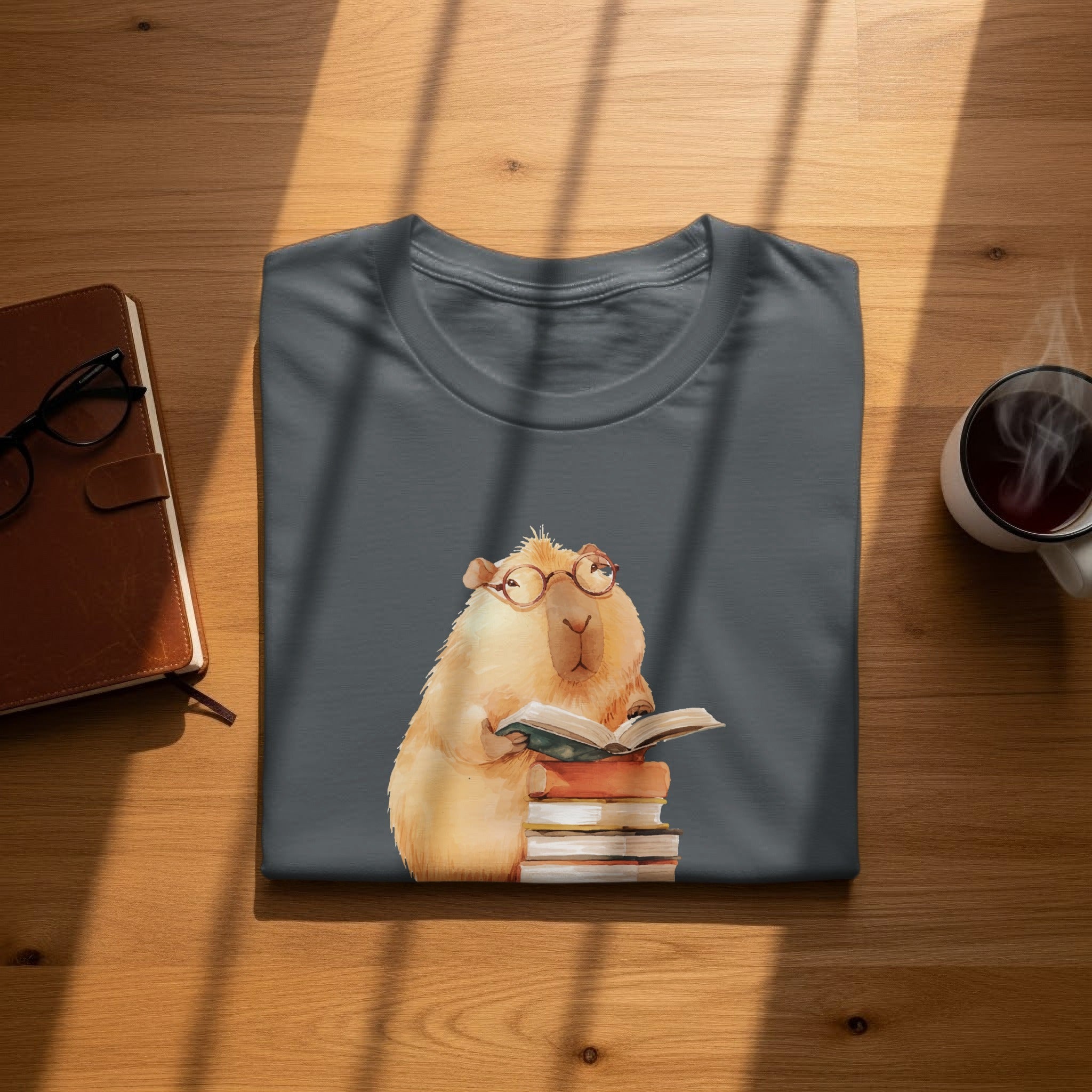Dark gray t-shirt with watercolor print of a capybara wearing glasses, reading books.