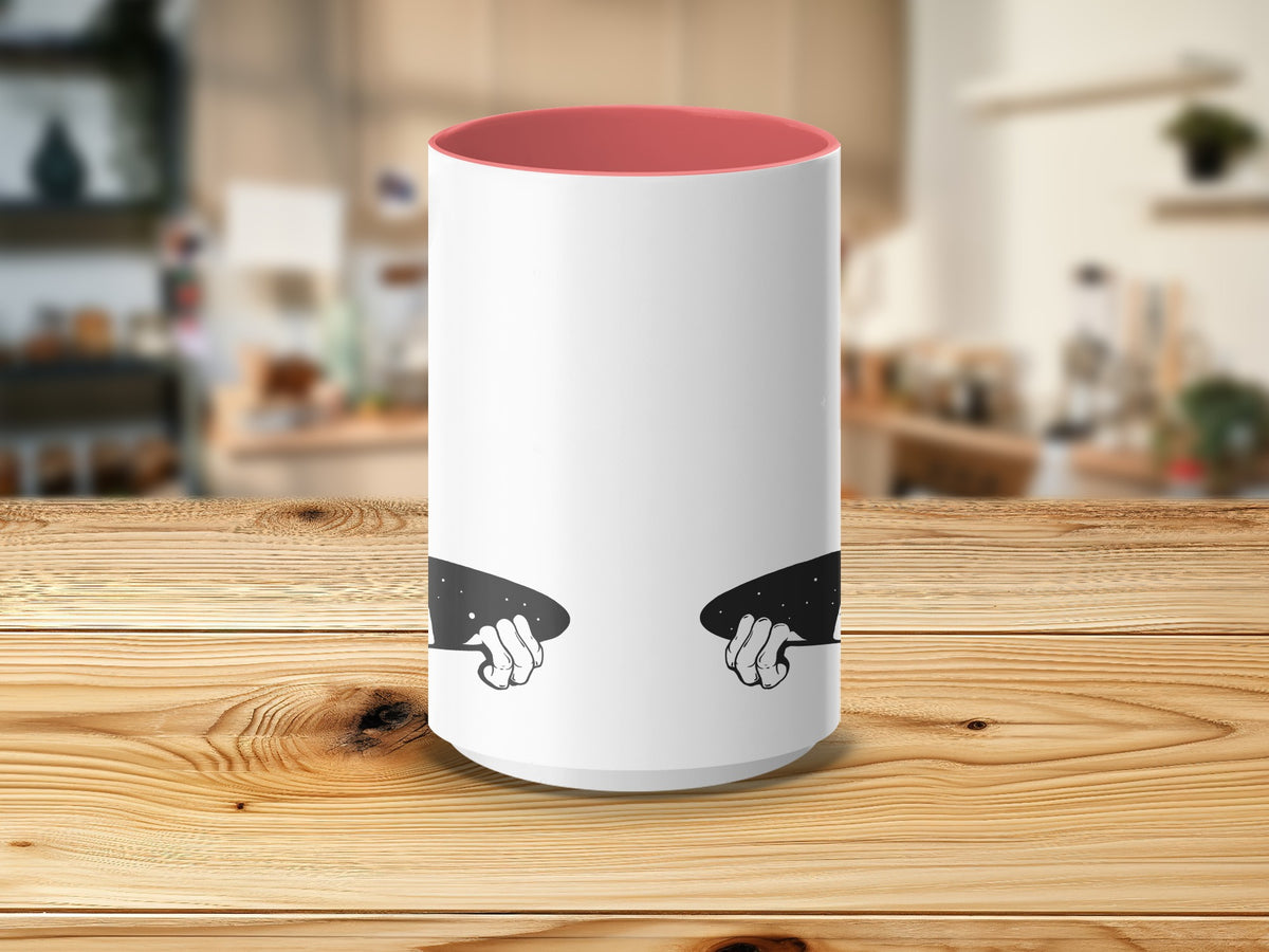 White mug with coral interior and cartoon hands holding starry cosmic shapes.
