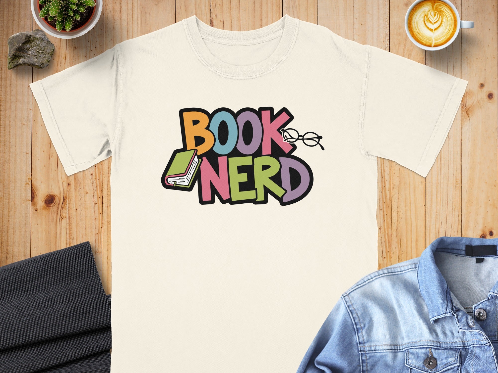 Cream t-shirt with colorful "BOOK NERD" text, book, and glasses graphics.