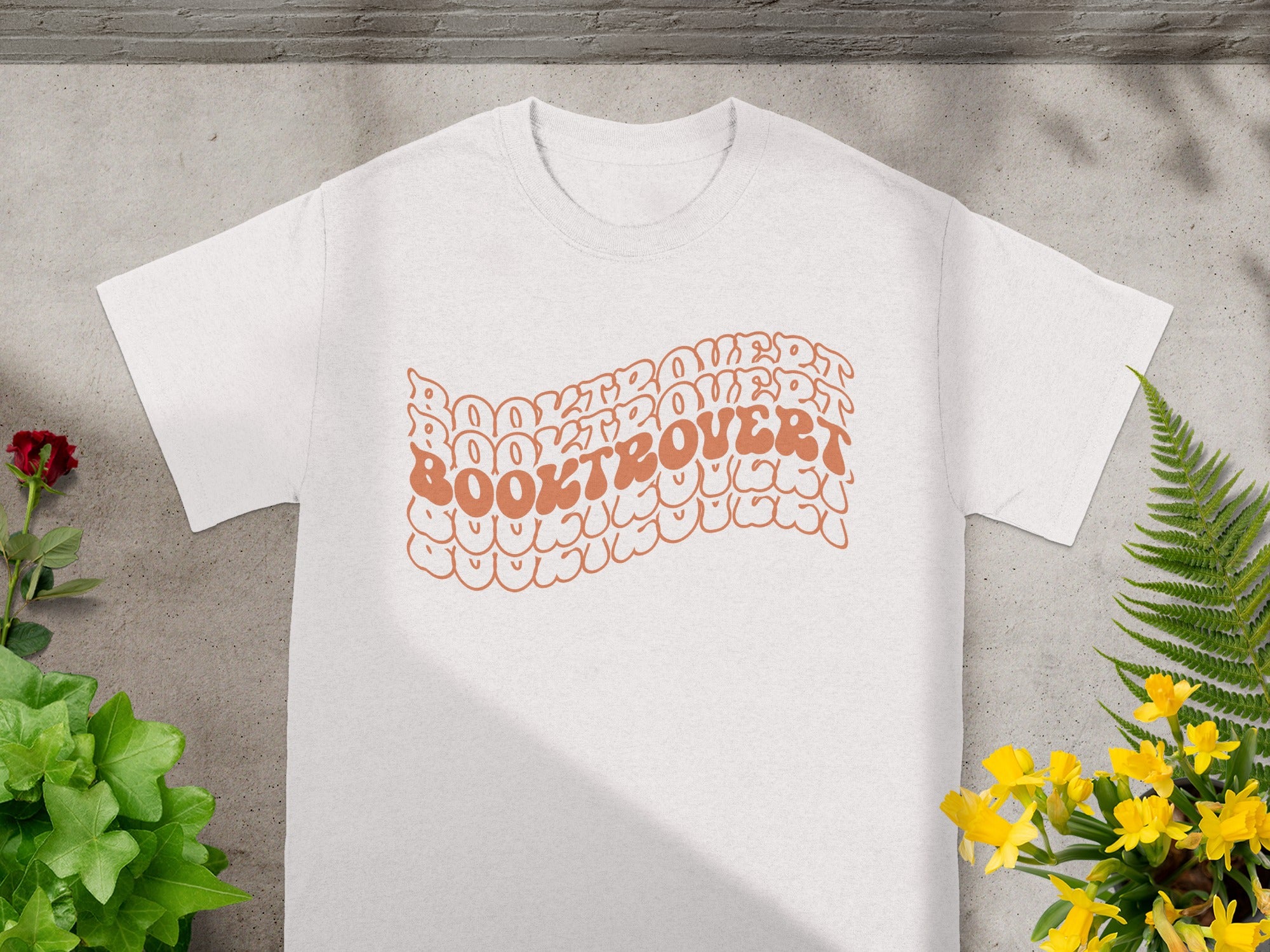 White t-shirt with "BOOKTROVERT" text in wavy orange font.