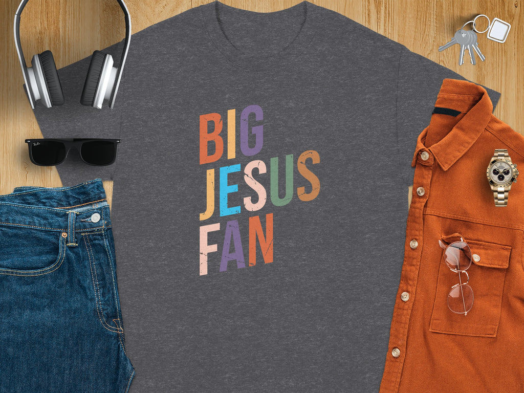 Dark gray t-shirt with colorful "BIG JESUS FAN" text, laid flat with accessories.