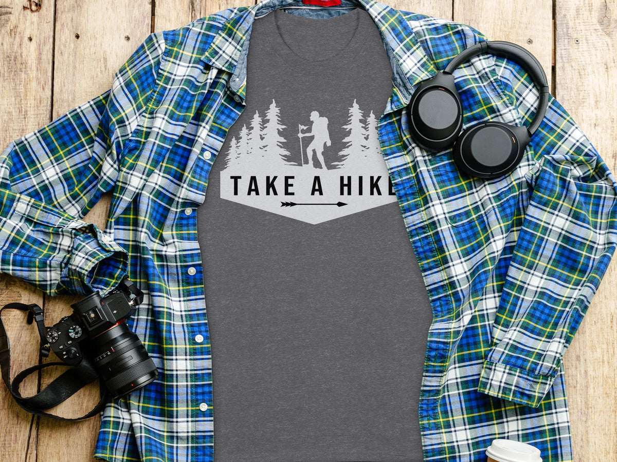 Gray t-shirt with "Take a Hike" graphic, plaid shirt, headphones, and camera.