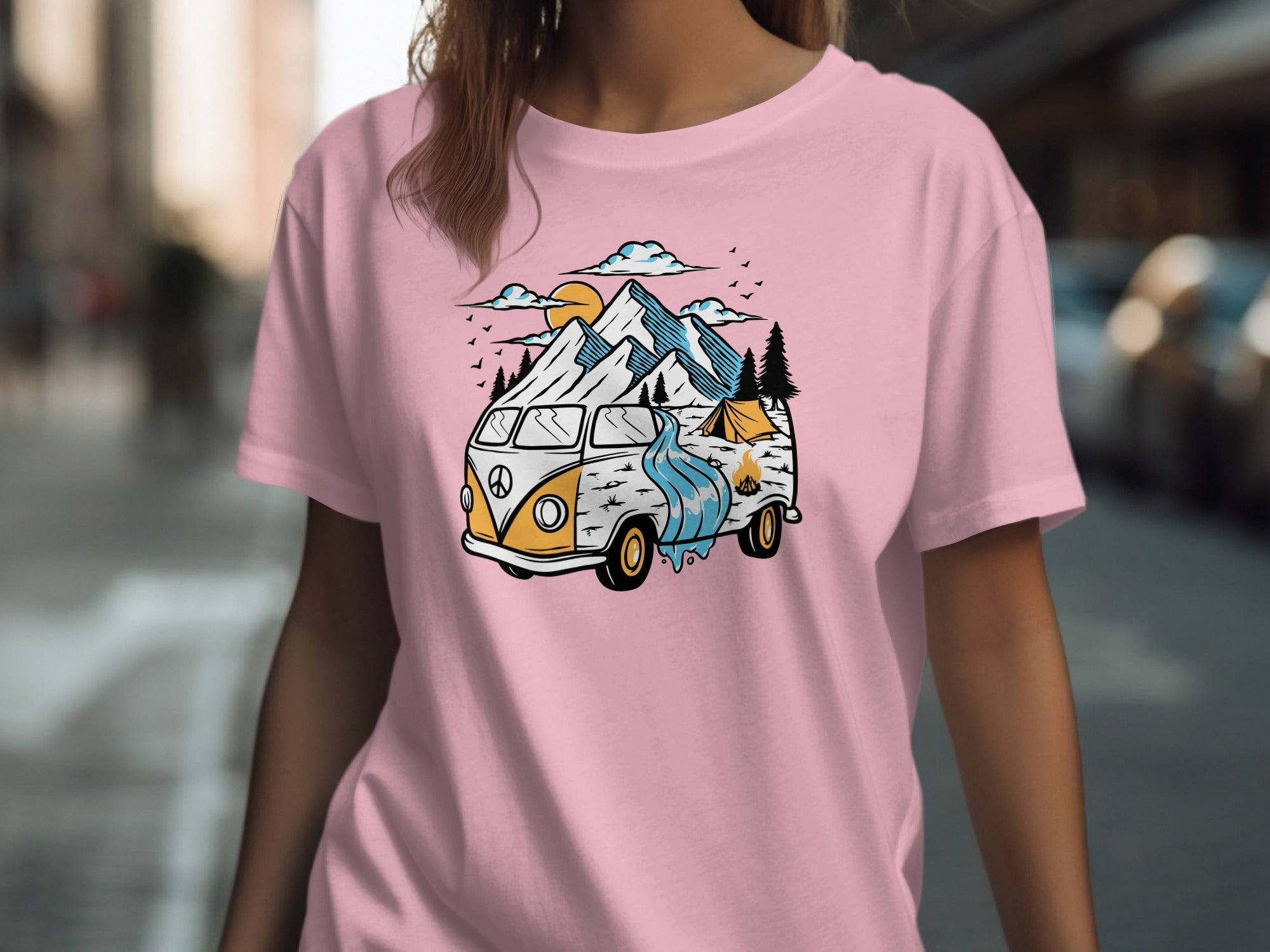 Pink t-shirt with a graphic of a vintage camper van, mountains, river, and tent.