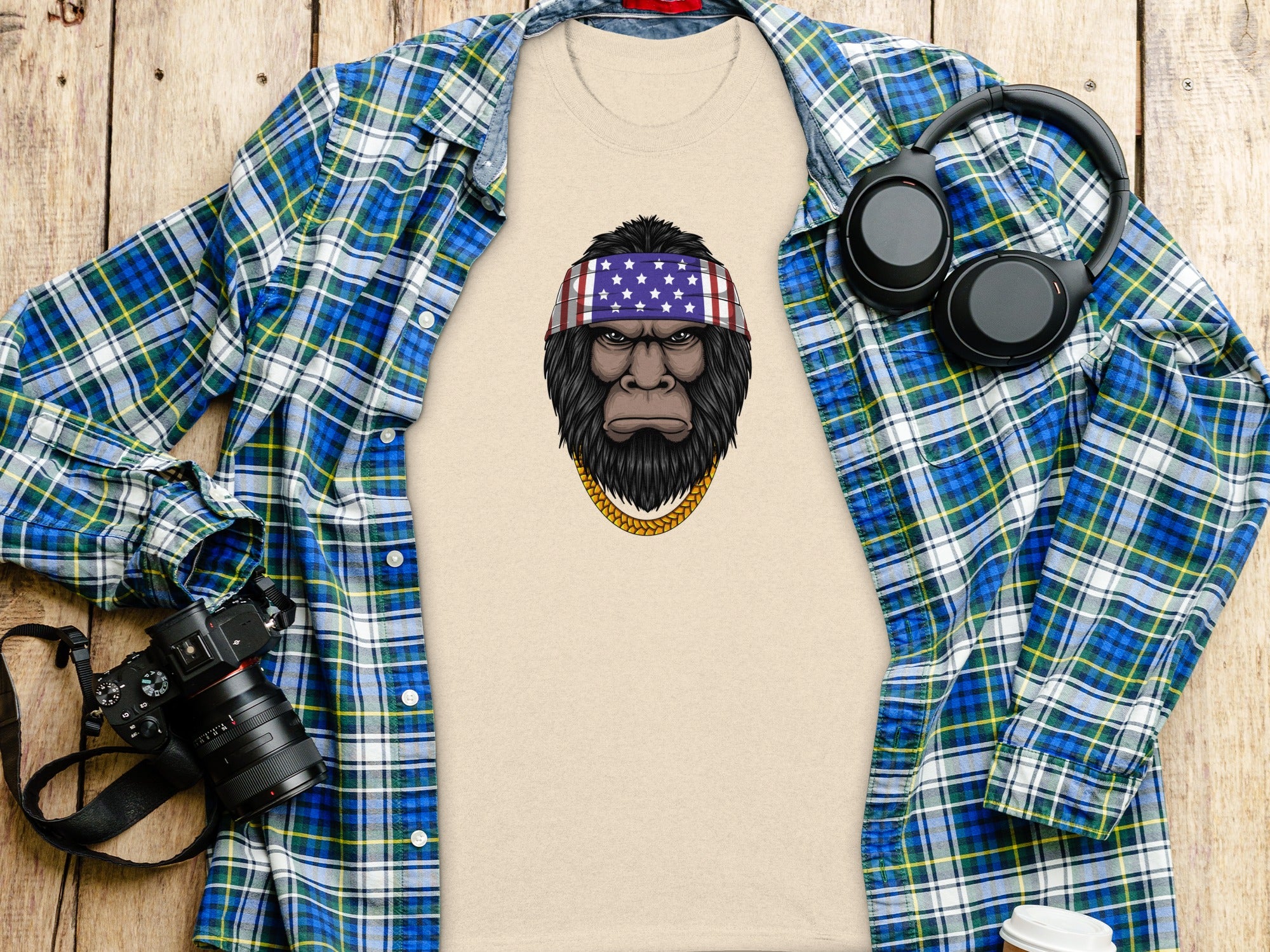 Beige t-shirt with Sasquatch graphic wearing American flag bandana and gold chain.