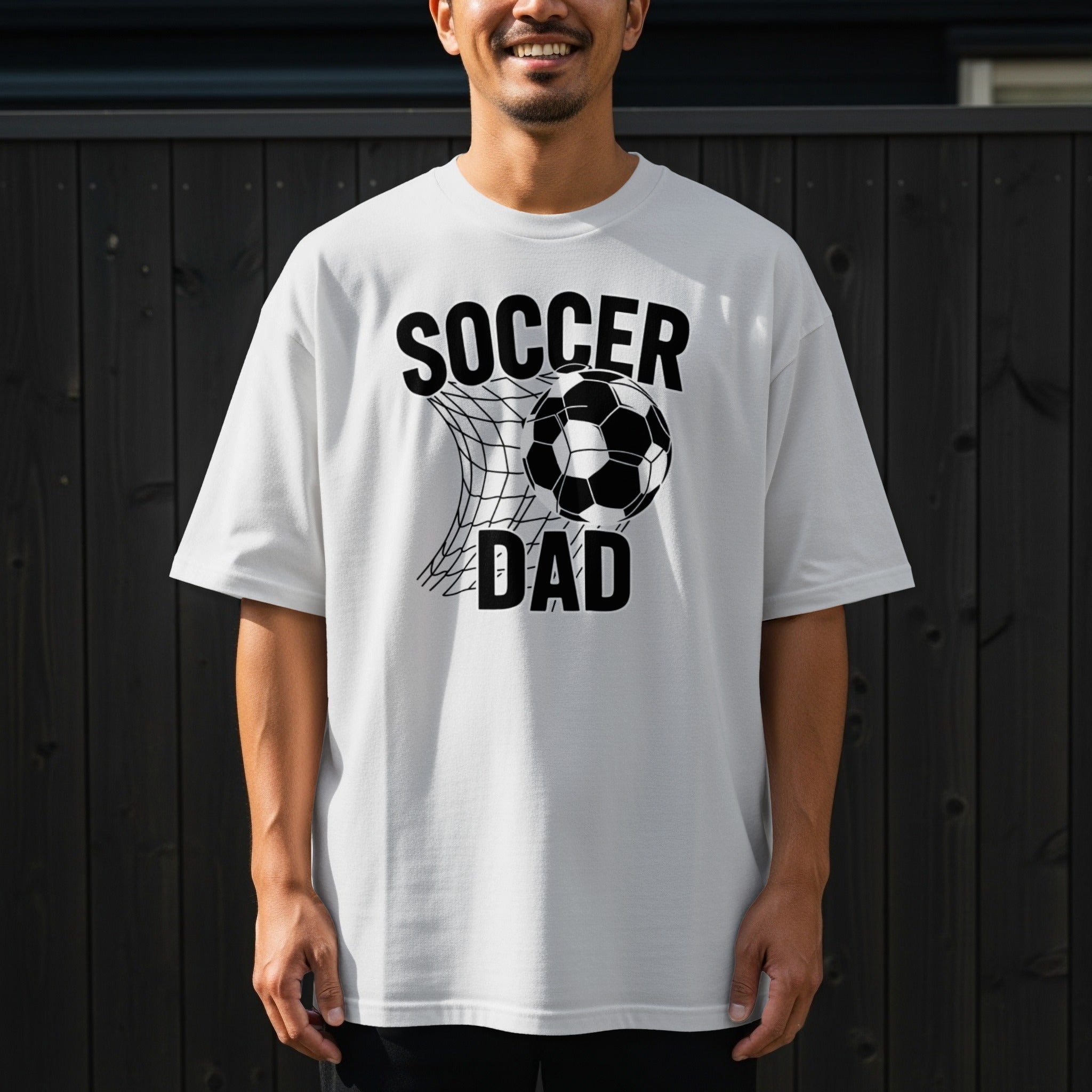 White t-shirt with black text and graphics "Soccer Dad" and a soccer ball in a net.