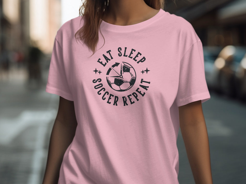 Pink t-shirt with "Eat Sleep Soccer Repeat" text and a soccer ball graphic.