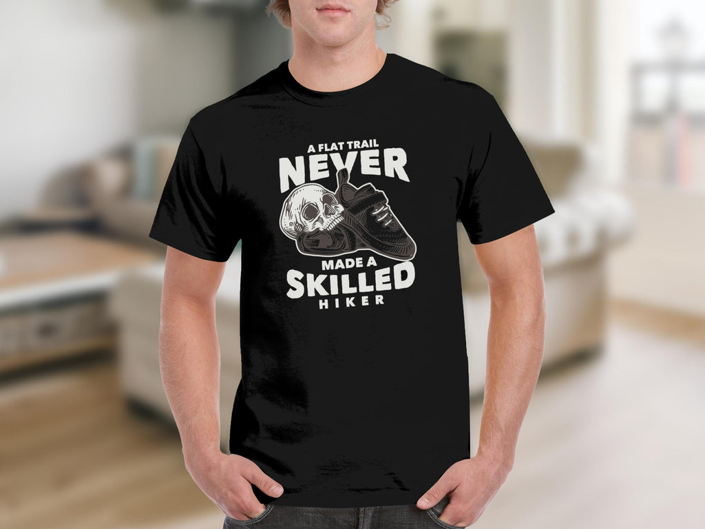 Black t-shirt with skull and boot graphic: "A flat trail never made a skilled hiker".