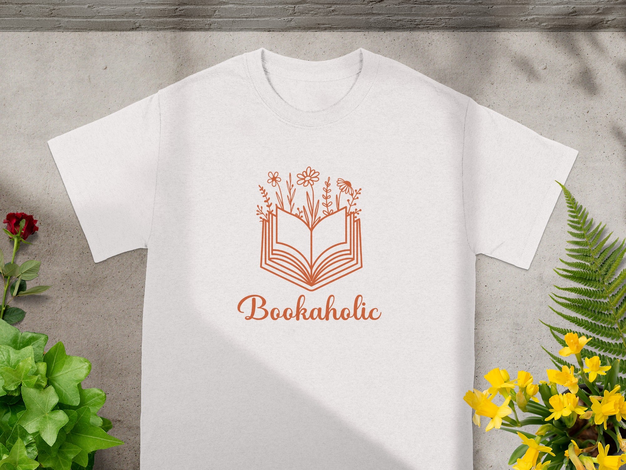 White t-shirt with orange book and flower graphic, reading "Bookaholic".