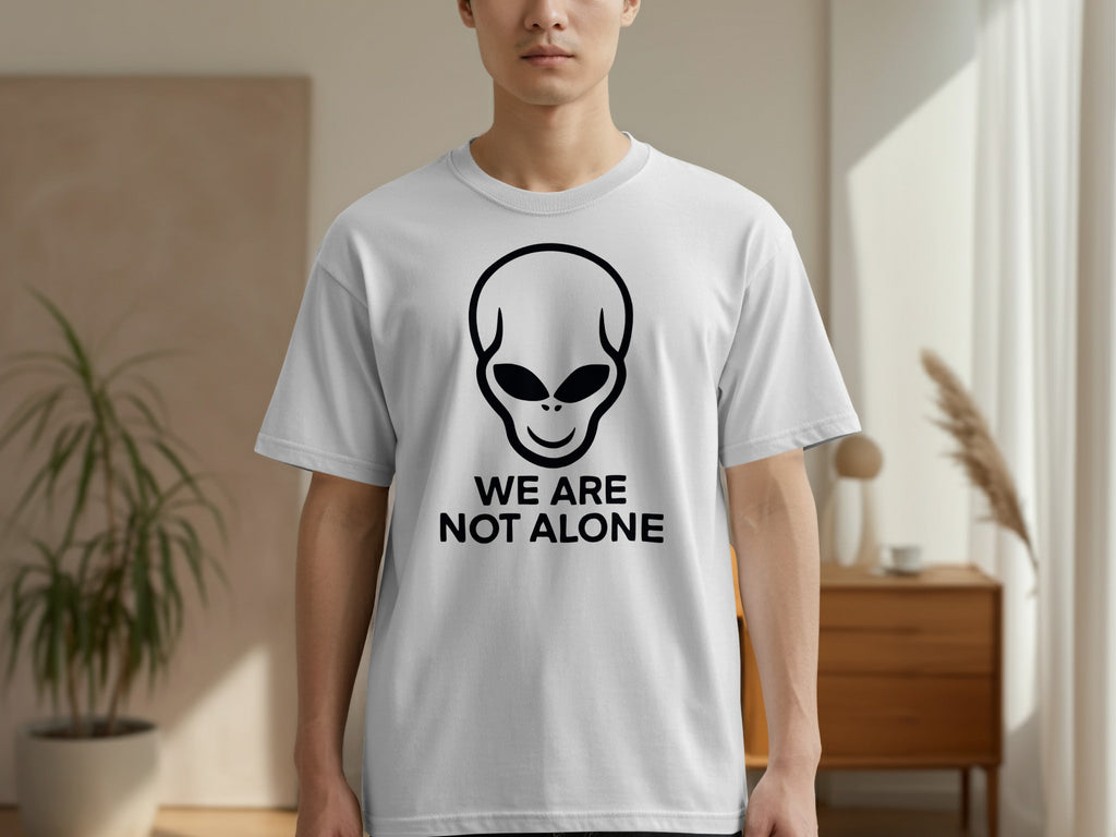 White t-shirt with black alien graphic and text "WE ARE NOT ALONE".