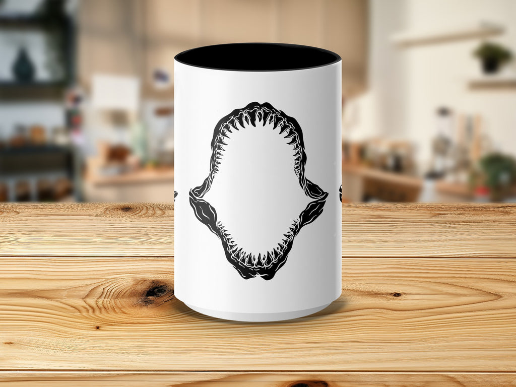 White mug with black shark teeth graphic on a wooden surface.