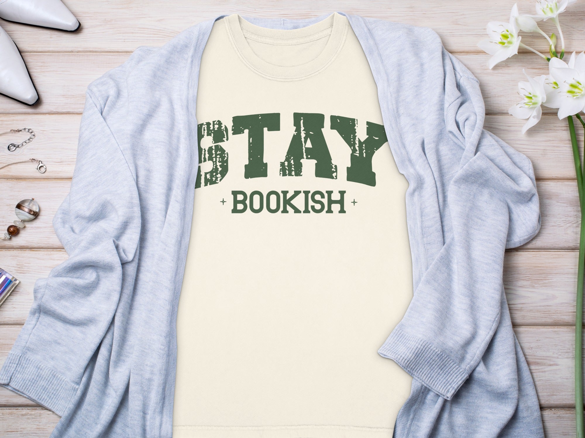 Tan t-shirt with distressed green "STAY BOOKISH" text, layered with a light blue cardigan.