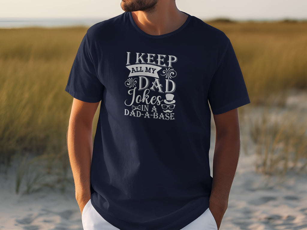 Dark navy t-shirt with white text reading "I KEEP ALL MY DAD Jokes IN A DAD-A-BASE."