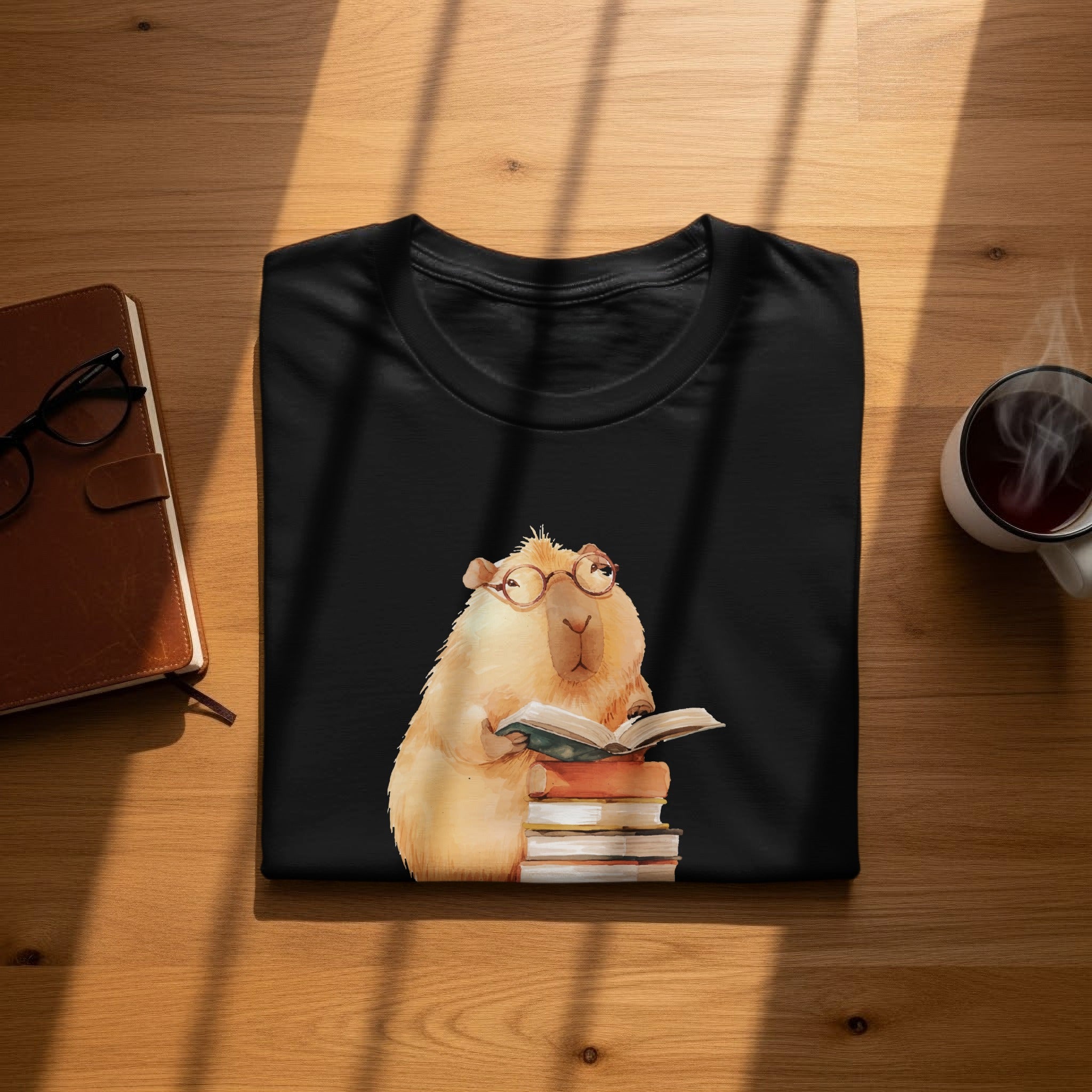 Black t-shirt with watercolor illustration of a capybara reading books.