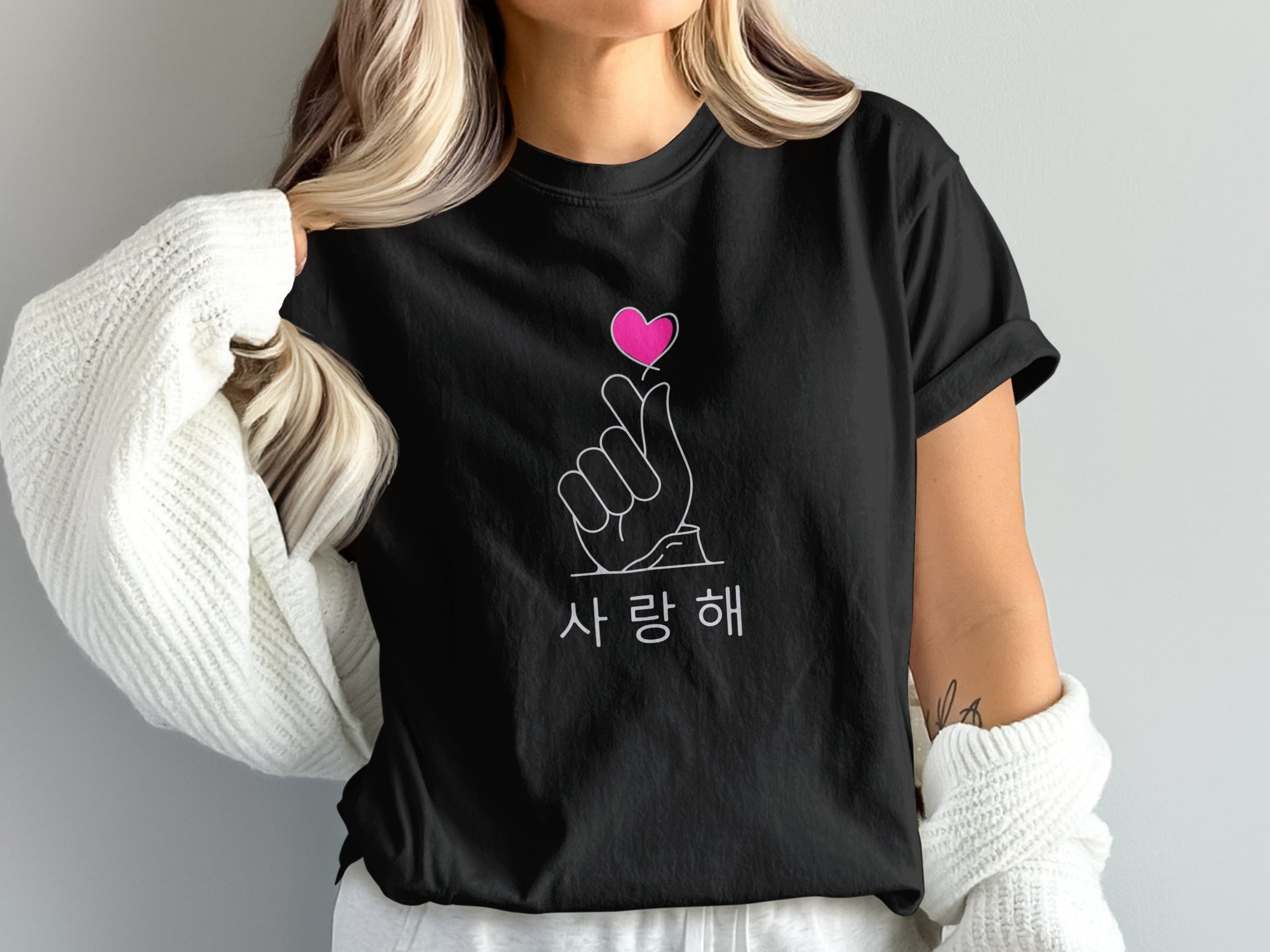 Black t-shirt with pink heart finger gesture and Korean text.
