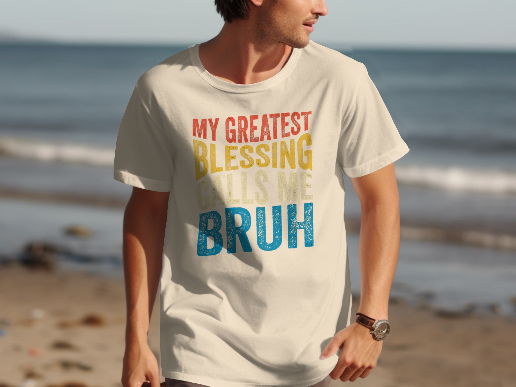 T-shirt with text "My Greatest Blessing Calls Me Bruh" on a man at the beach.