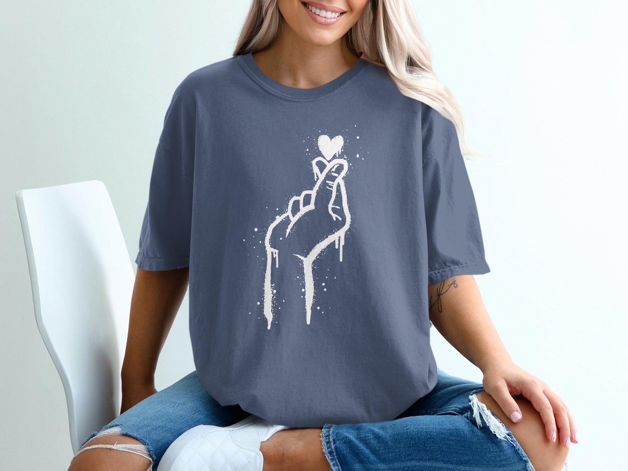 T-shirt with white splatter graphic of hand making a heart shape.