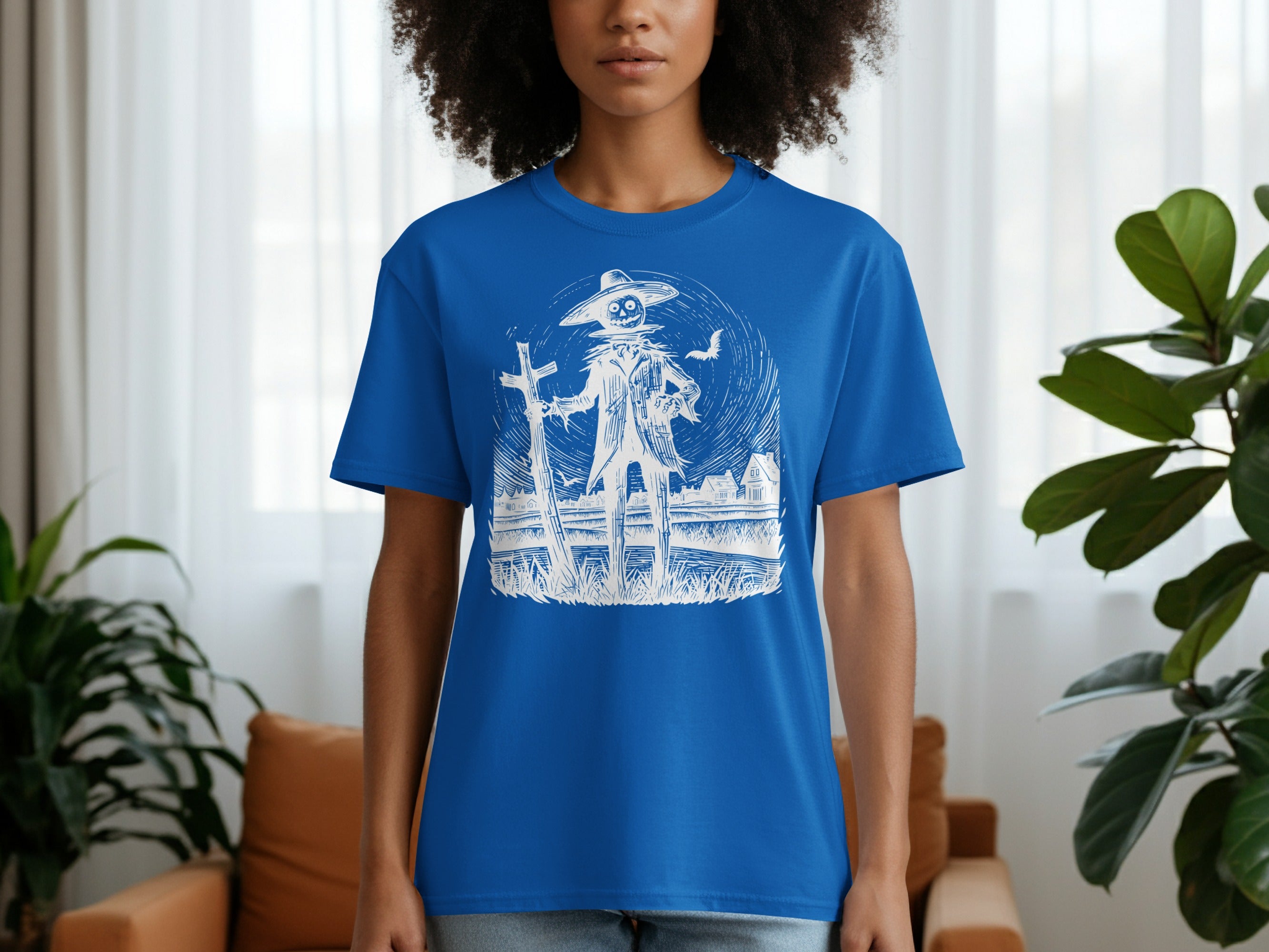 Blue t-shirt with scarecrow, cross, and house graphic illustration.